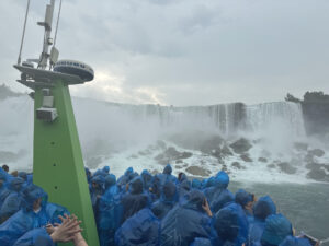 Passagier der Maid of the Mist blicken in blauen Regencapes auf die Niagarafälle