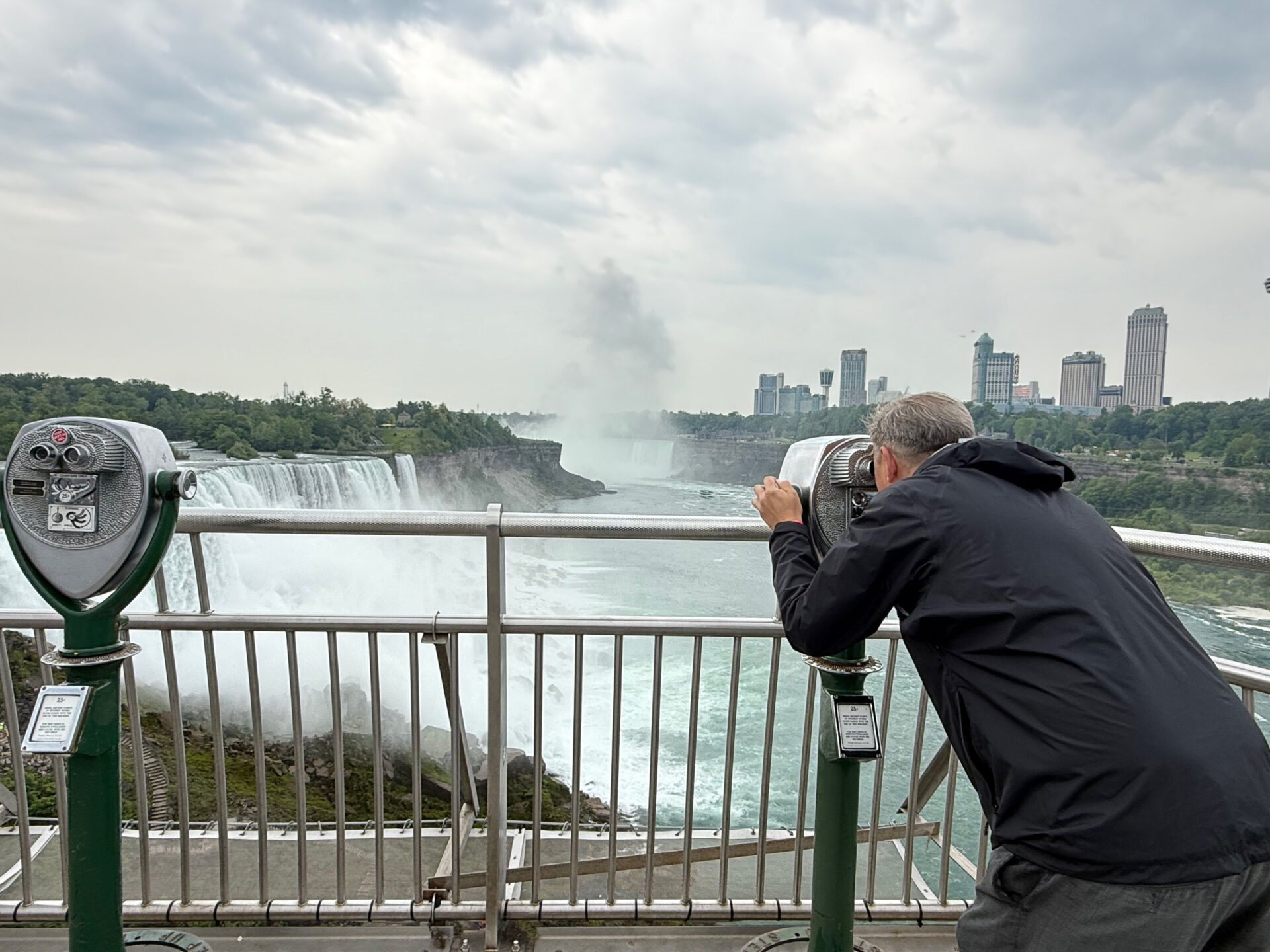 Mann schaut durch ein Fernglas auf die Niagarafälle