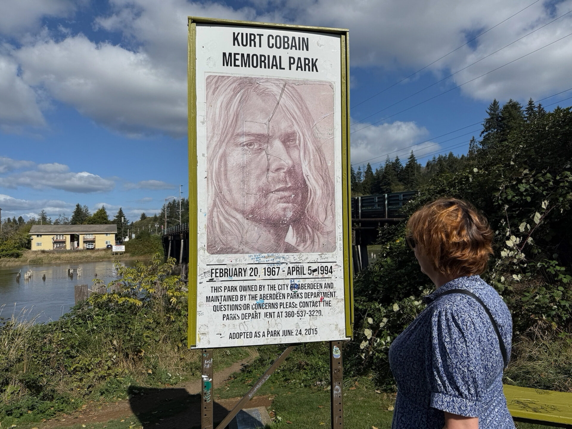 Frau blickt auf ein Schild mit dem Konterfei des Nirvana-Sängers. Kurt Cobains Geburtsort ist Aberdeen, Washington 