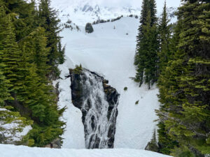 Wasserfall im Schnee umgeben von grünen Nadelbäumen im Mount Rainier National Park