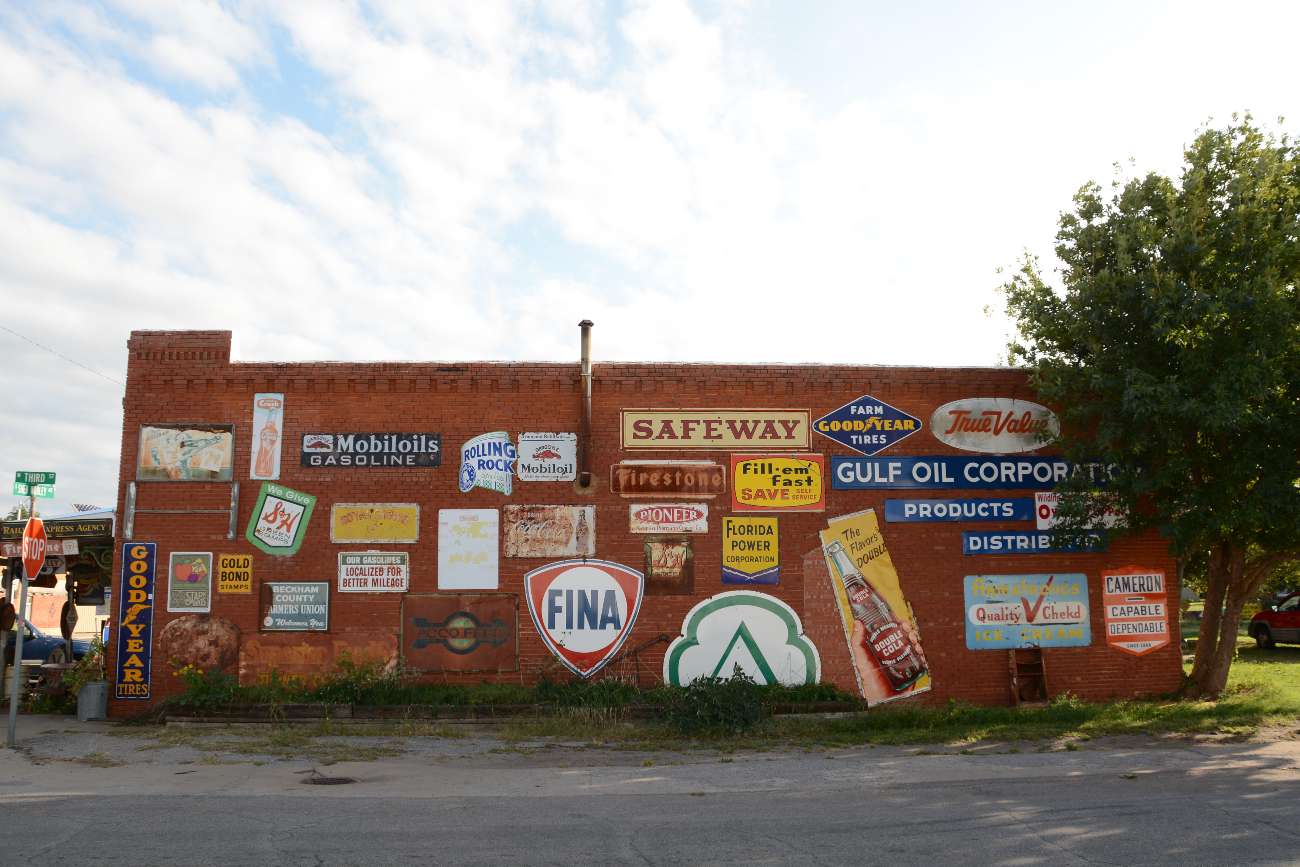 Große Sammlung an Vintage-Schildern auf einer Hauswand in Erick, Oklahoma, an der Route 66