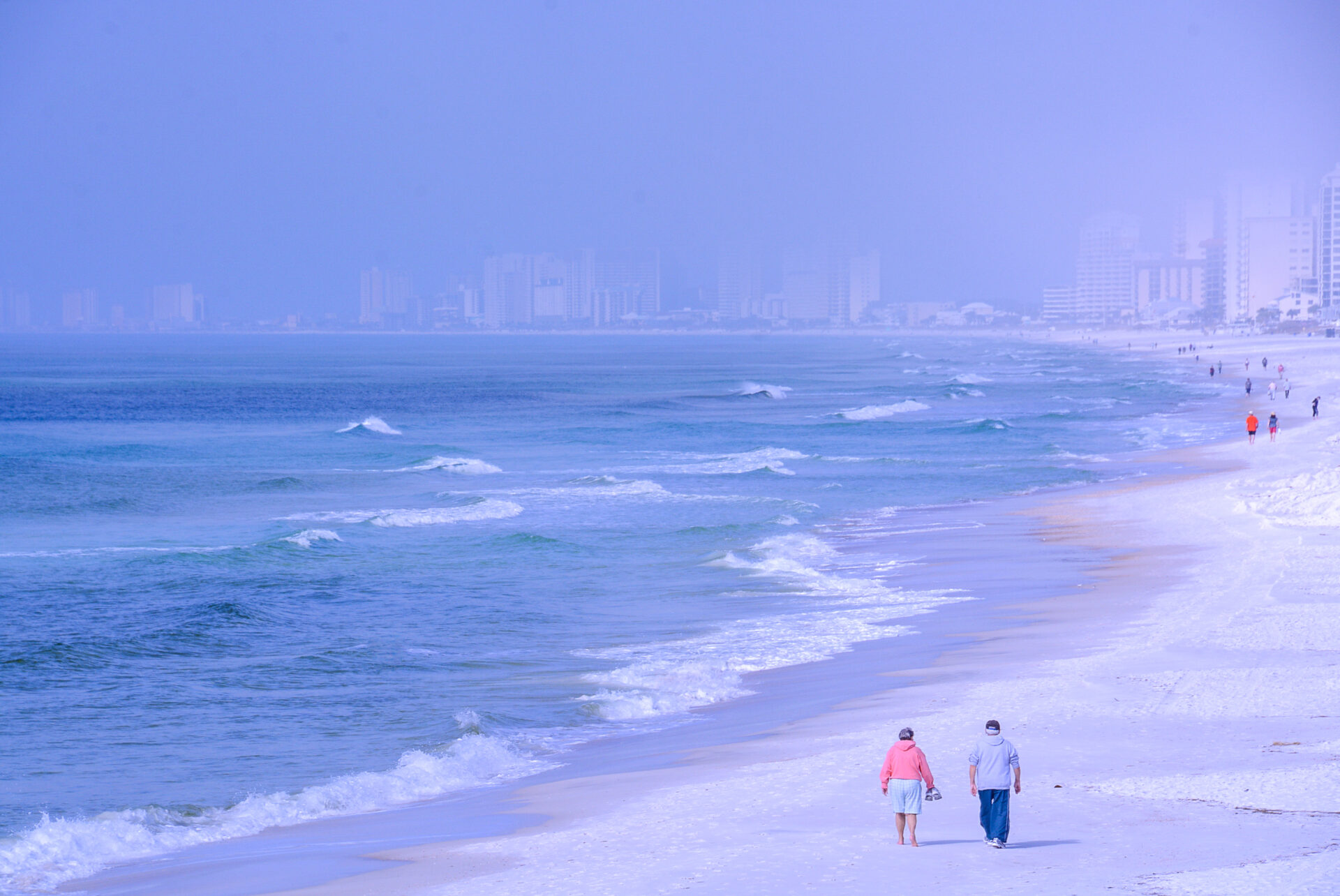 Spaziergänger am Strand von Panama City Beach mit Ferienbauten im Hintergrund