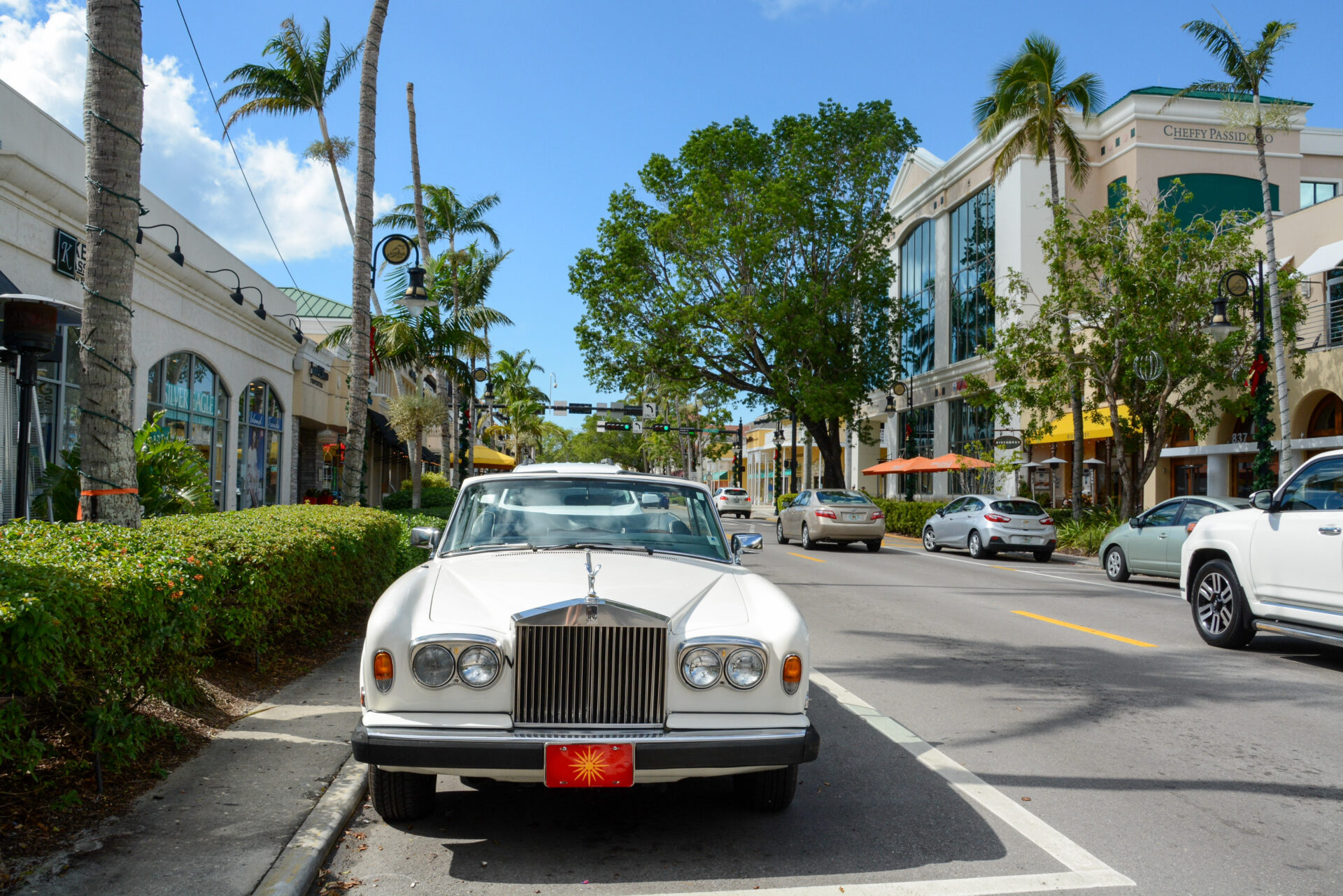 Ein weißer Rolls Royce auf der Fifth Avenue in Naples an der Golfküste Floridas, im Hintergrund Palmen und Geschäfte